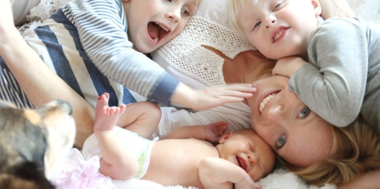 Mother cuddling on bed with children